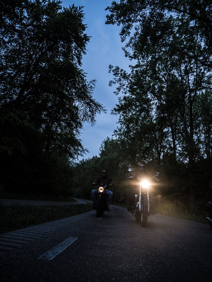 Two Men Riding Motorcycle on Road during Nighttime